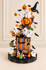 Halloween cake with orange pumpkins, white ghosts, black bats and colourful candy decorations